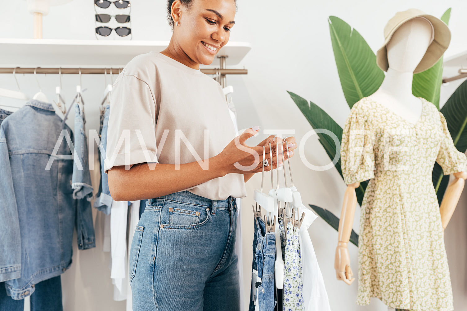 Woman working in a clothing shop. Young boutique owner holding hangers.