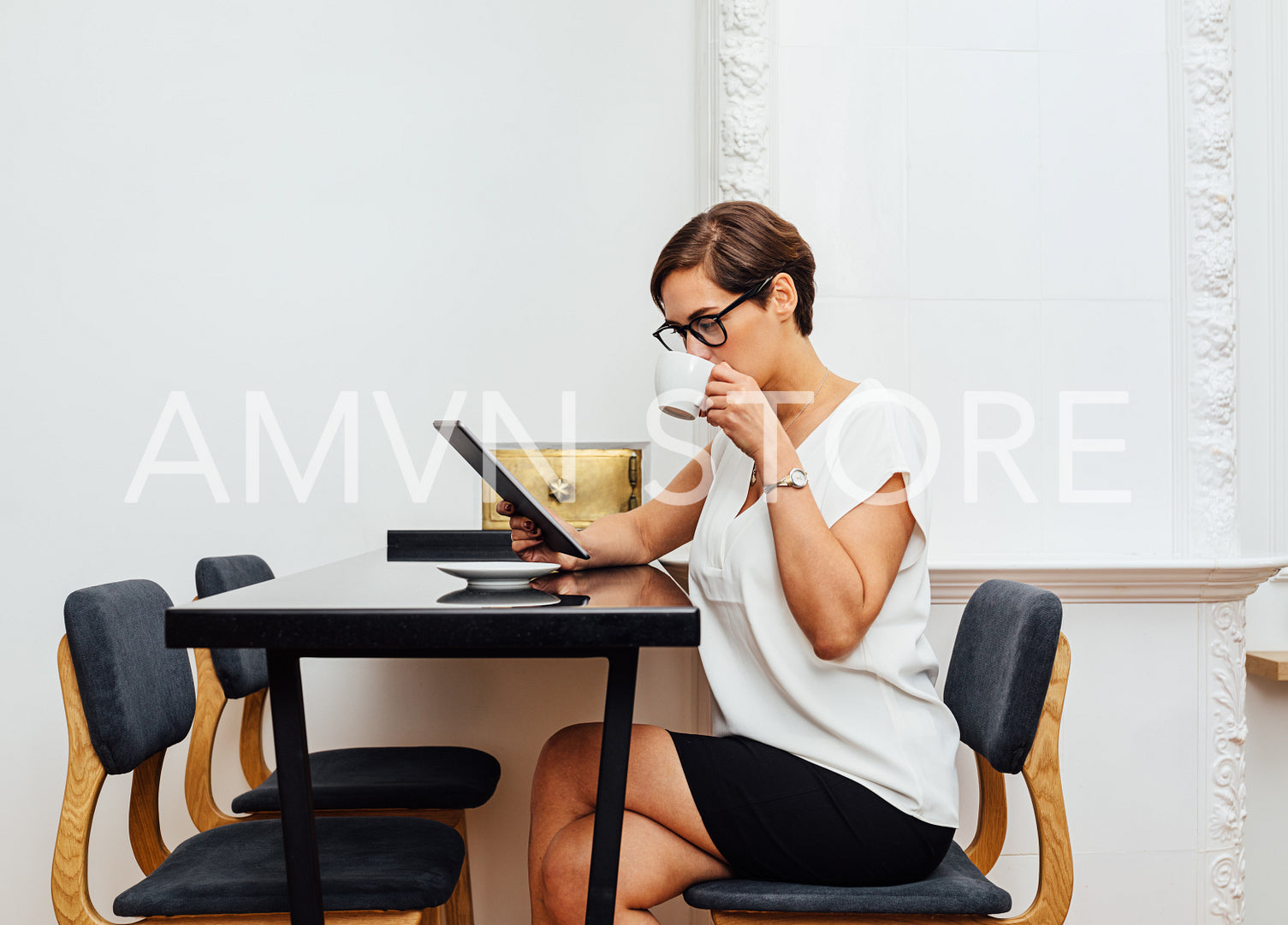 Side view of caucasian businesswoman drinking a coffee in apartment. Female entrepreneur reading from a digital tablet in her apartment at morning.	