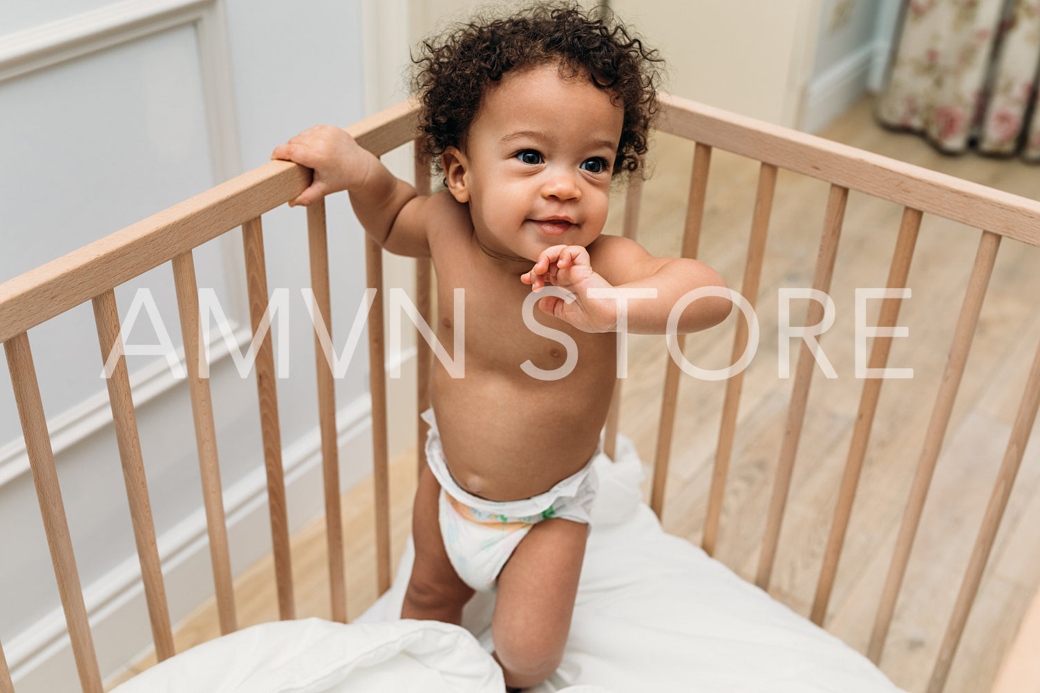 Toddler boy standing in a crib. Smiling child trying to walk.	