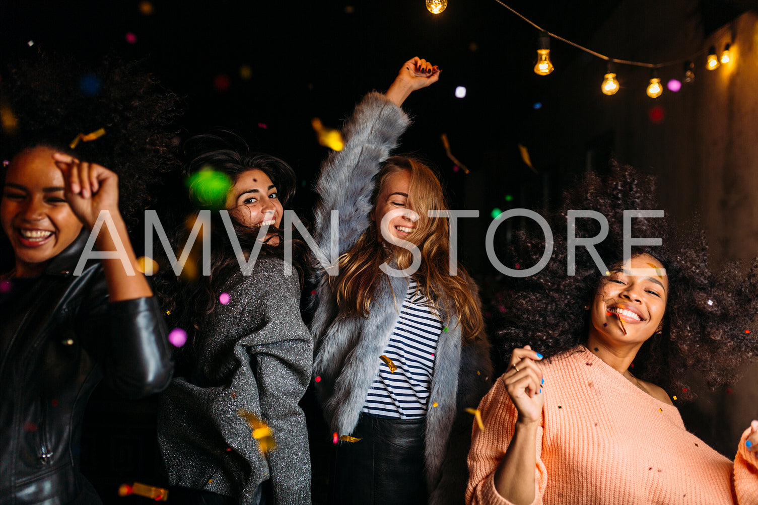 Group of female friends dancing at night under confetti	