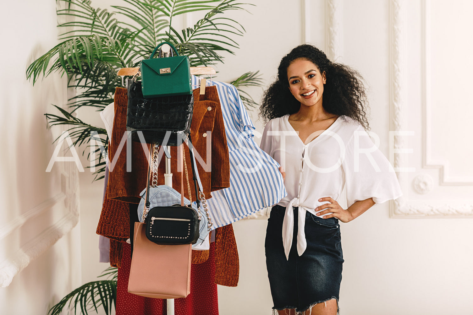 Smiling stylist standing at her wardrobe and looking at camera	