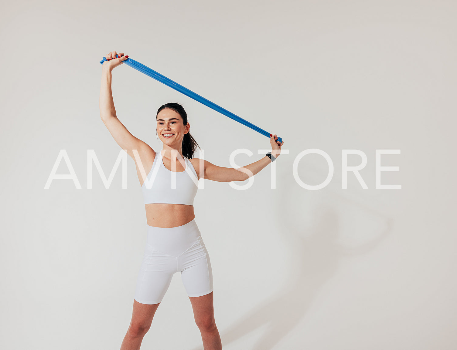 Healthy smiling woman in white fitness wear warming up with a resistance band