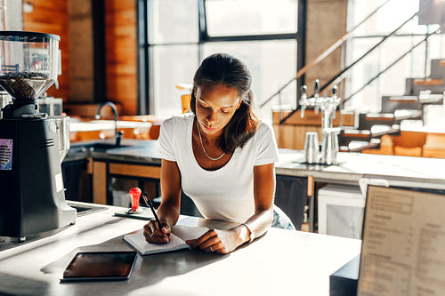 Businesswoman doing paperwork in her cafe at counter