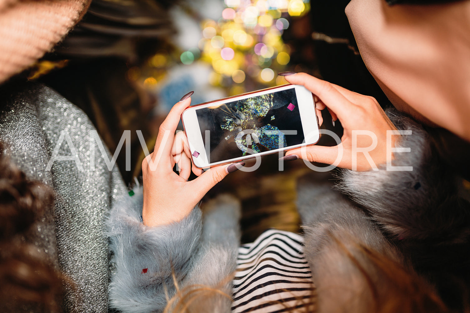 Hands of unrecognizable woman taking photo of confetti with cell phone	