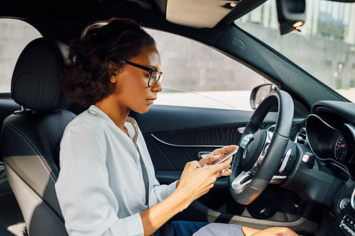 Side view of young businesswoman holding a cell phone in car