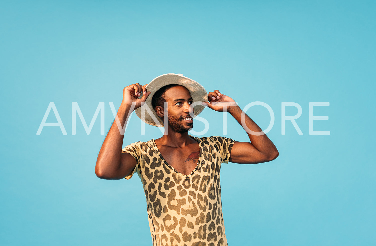 Stylish male holding his straw hat with hands and looking away