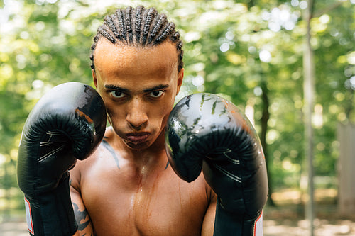 Close up portrait of a sweated kickboxer with gloves and mouth guard looking at the camera