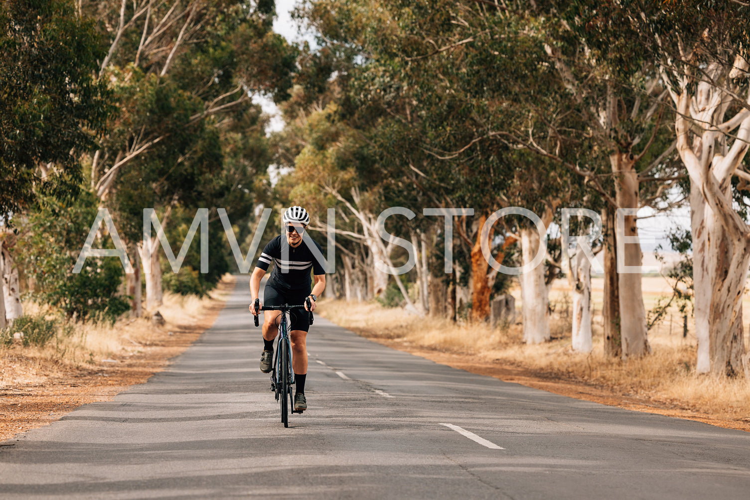 Smiling woman in sportswear riding her bike on empty countryside road 