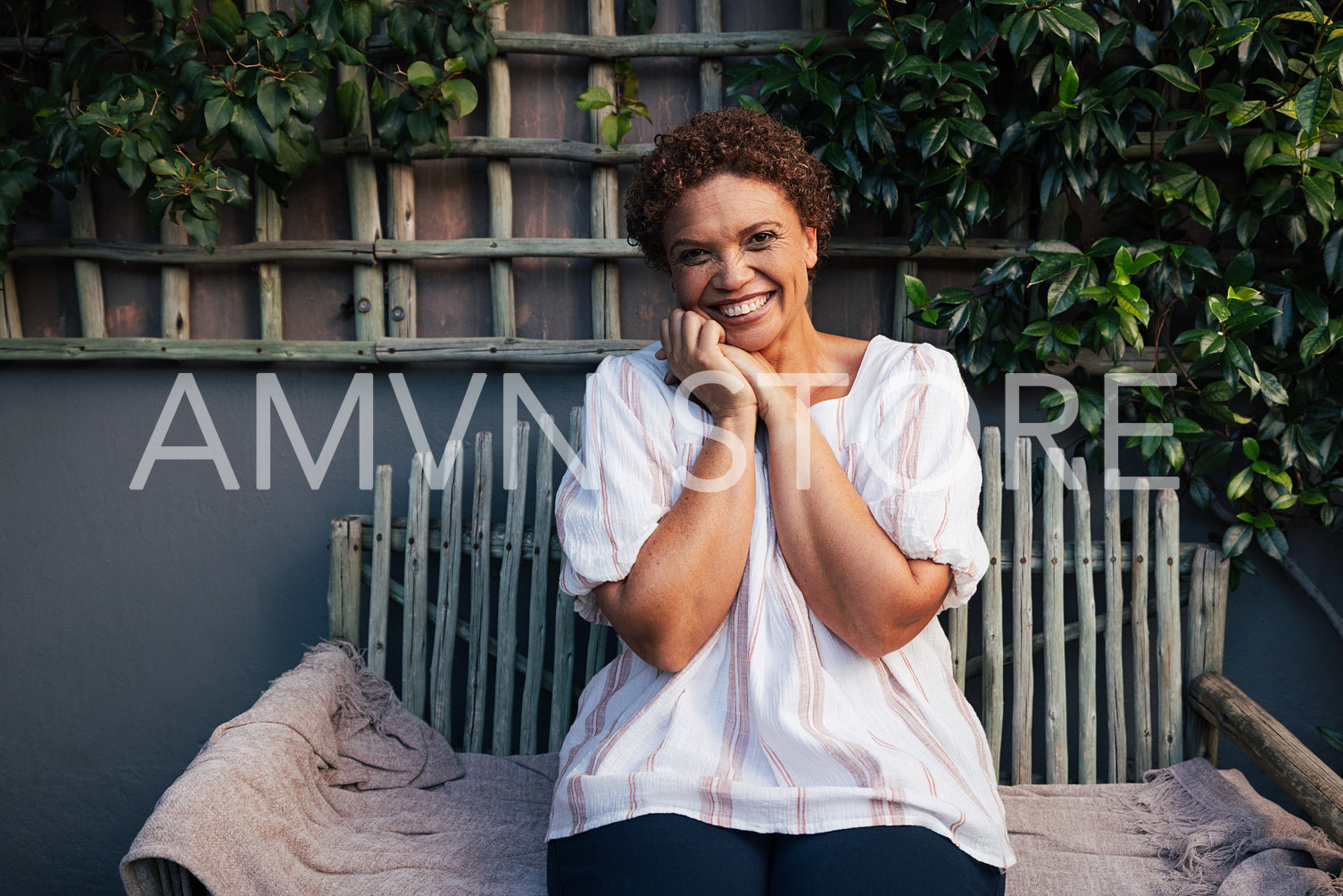 Portrait of a mature woman laughing while looking at camera. Middle aged female with short hair sitting at backyard.