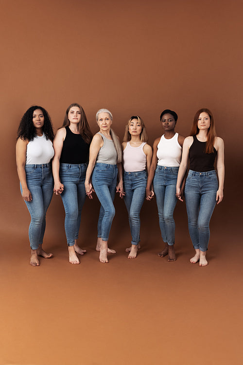 Six diverse women holding hands. Group of multi ethnic females of different ages looking at camera.