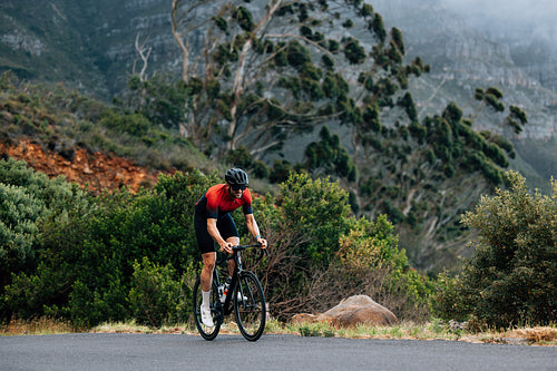 Young male doing intense training on bicycle in wild terrain. Man doing a training on bicycle.