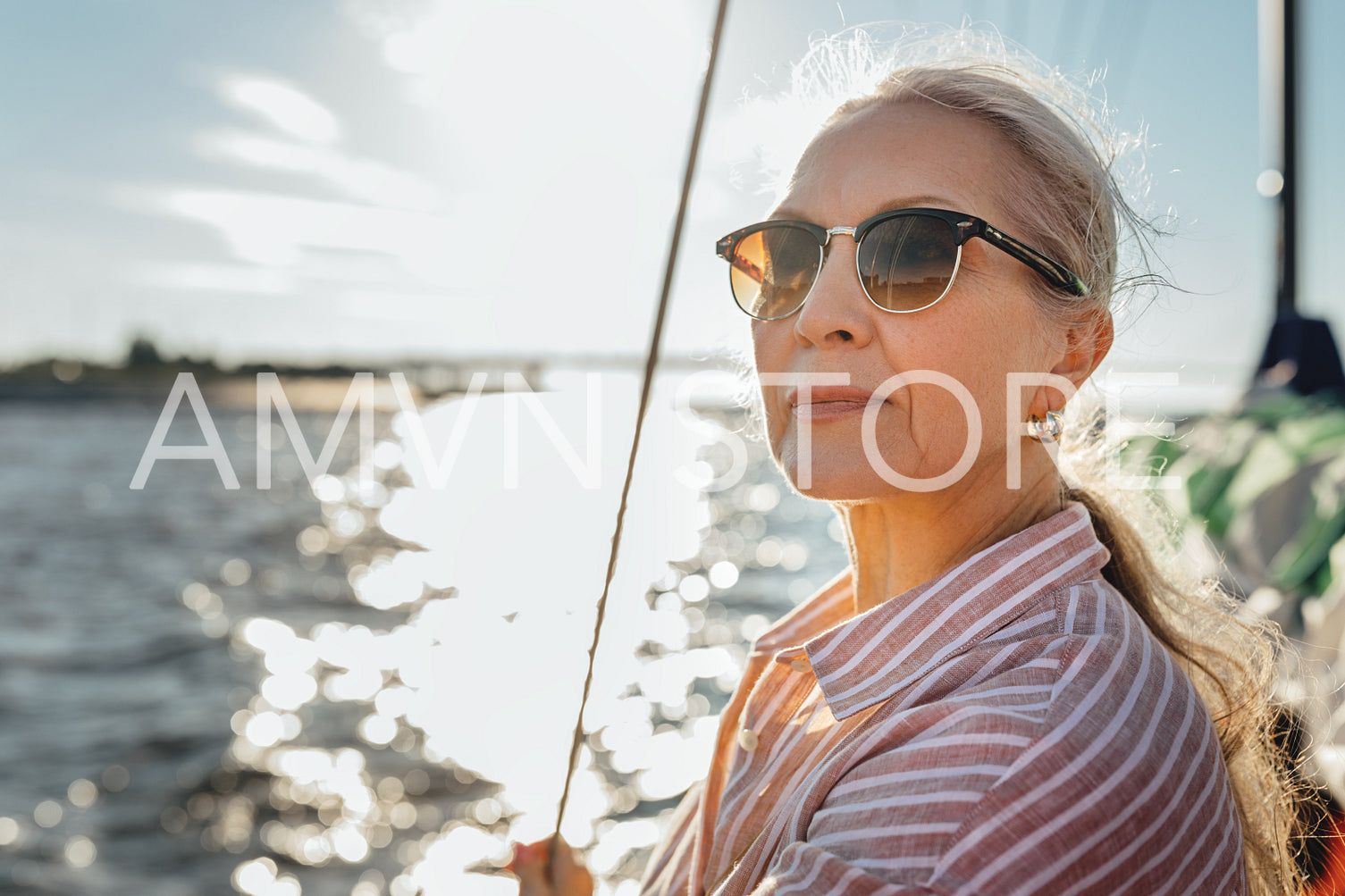 Portrait of a mature woman wearing sunglasses standing on a sailboat and looking into distance	