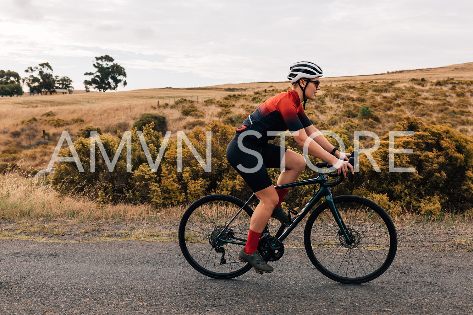 Side view of fit and determined sportswoman cycling road bike on a countryside road