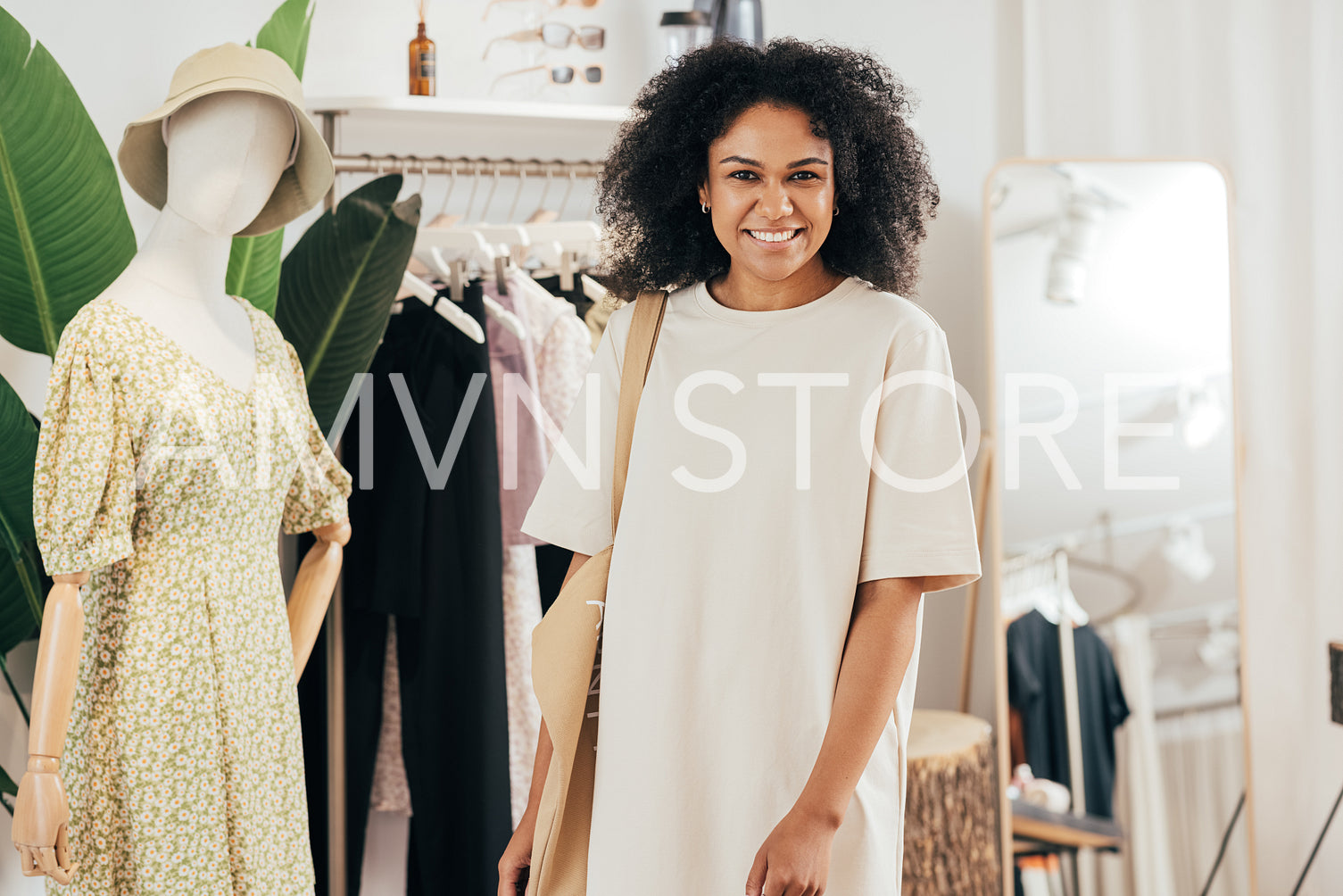 Portrait of a woman in stylish clothes and shopping bag standing in a small boutique