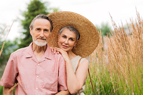 Portrait of an aged people standing together on the field. Mature husband and wife looking at the camera.