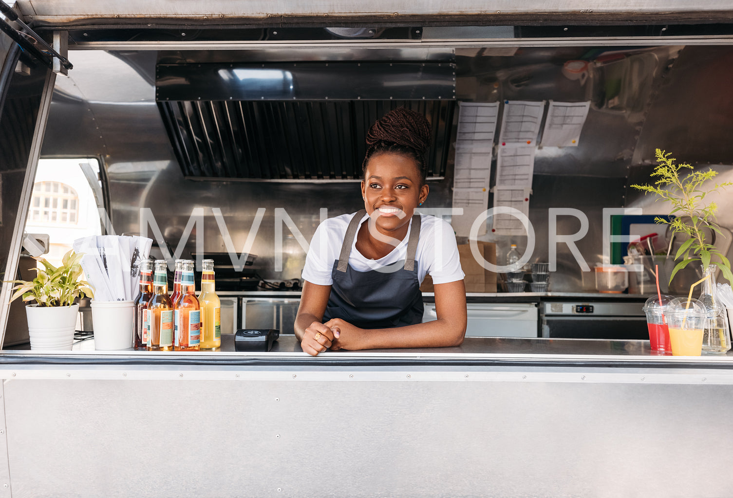 Portrait of young saleswoman waiting for clients. Food truck owner leaning on a counter looking away.