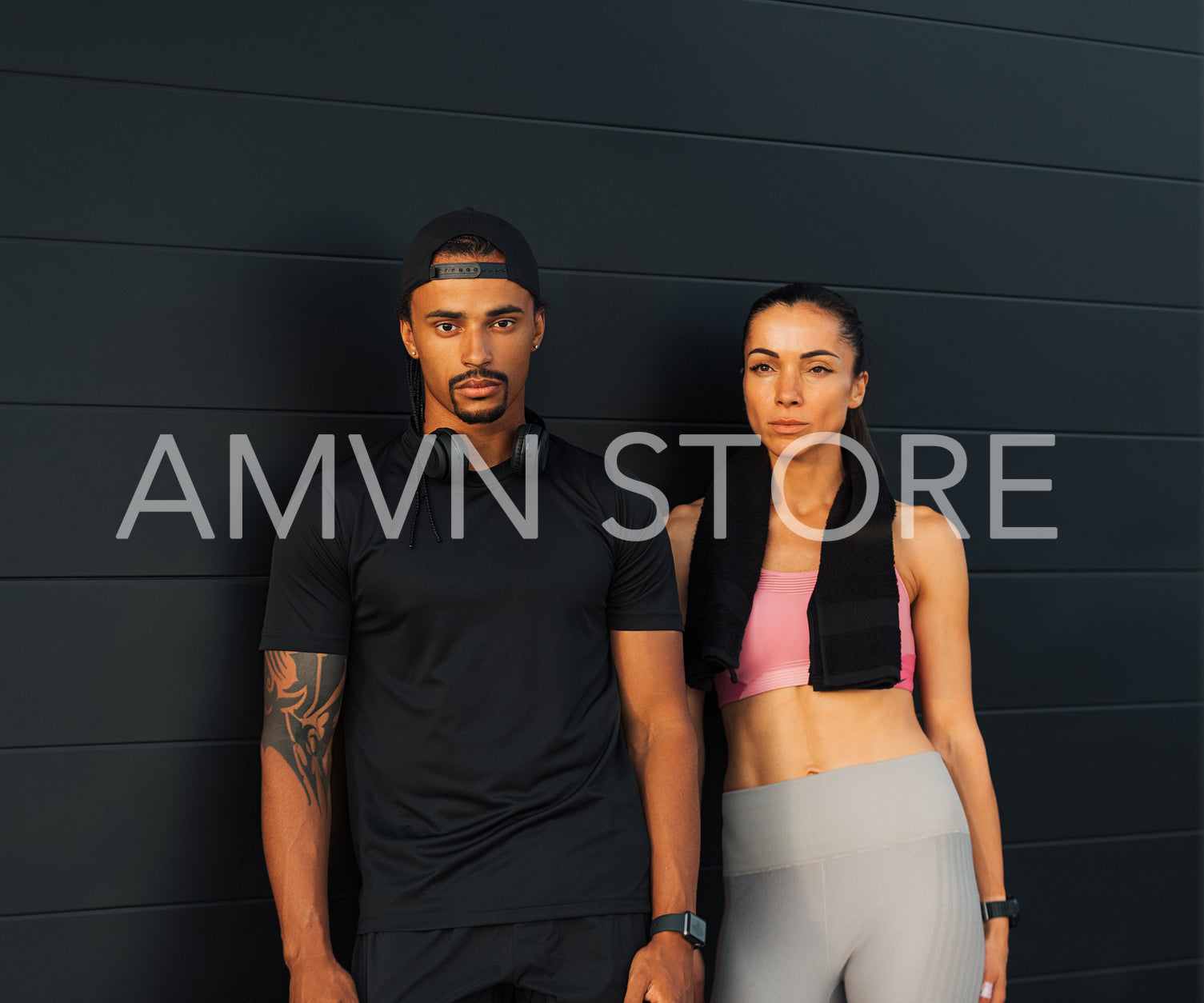 Multiethnic fit couple in sportswear relaxing at a black wall outdoors