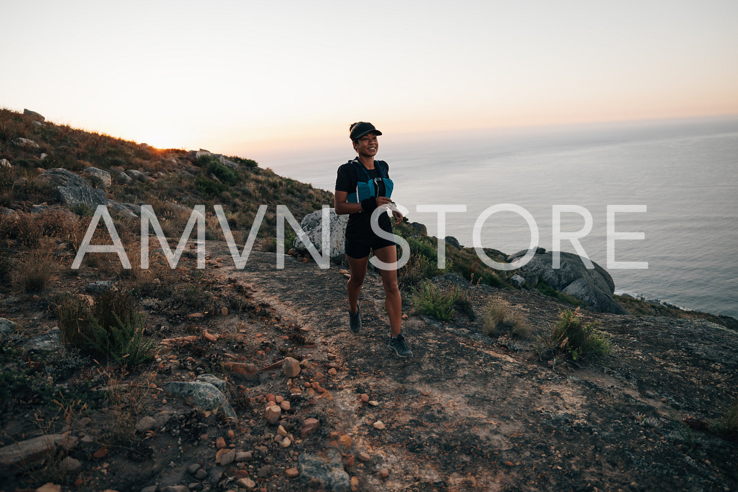 Trail runner exercising at sunset on mountain. Woman running on a hill.