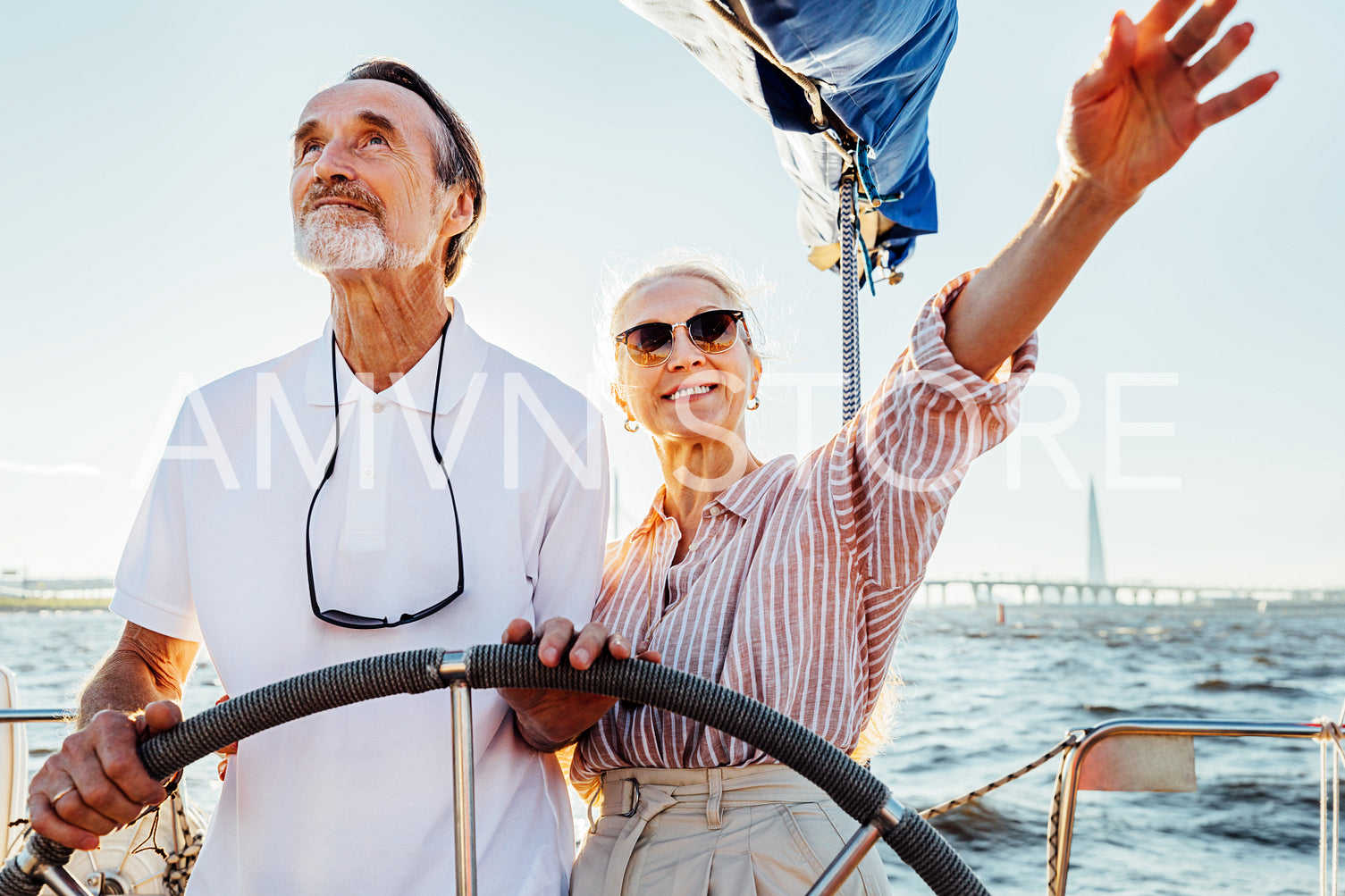 Mature couple standing at steering wheel on their yacht and enjoying vacation	