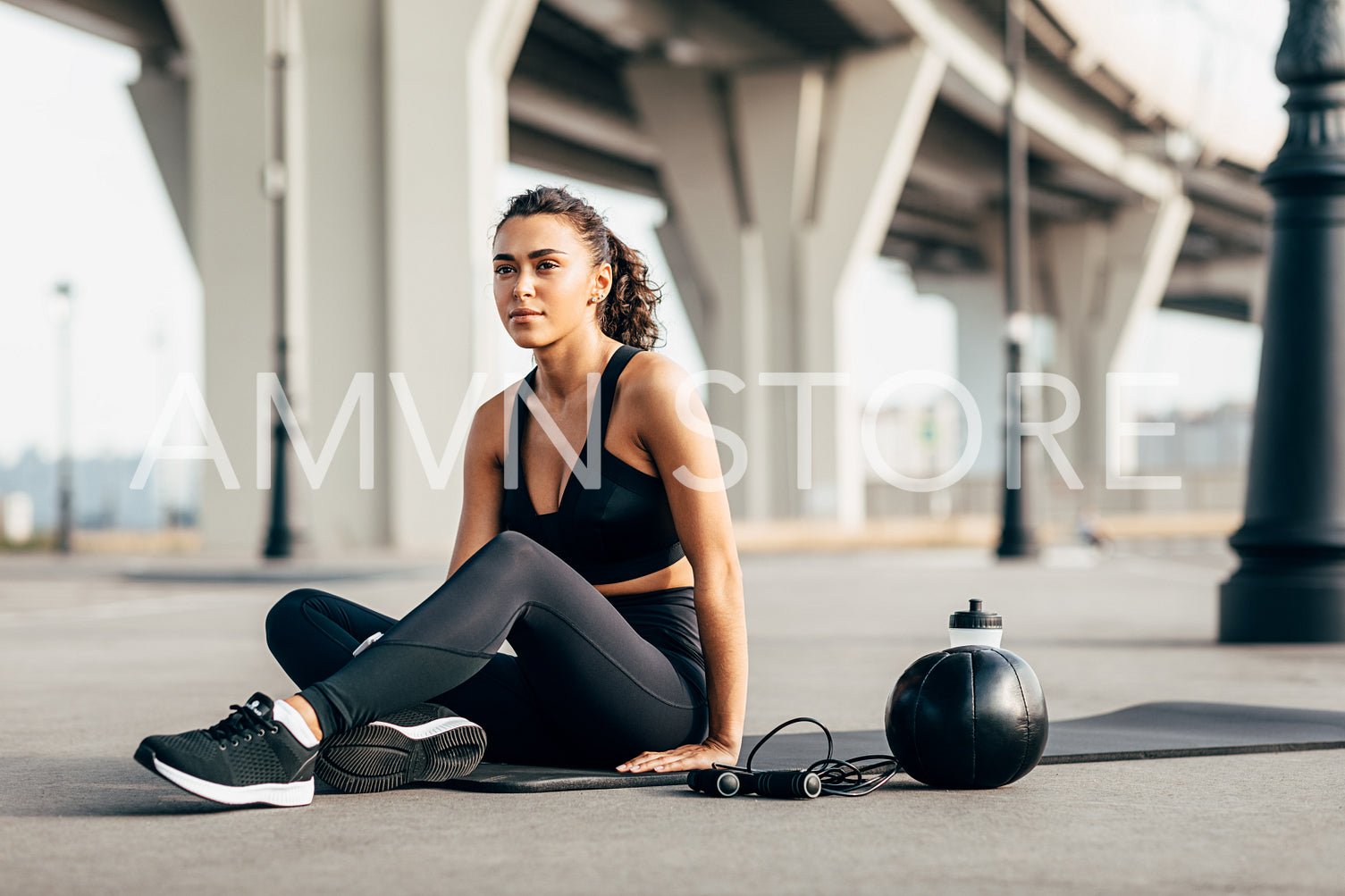 Woman in sportswear resting on mat after workout on city street	