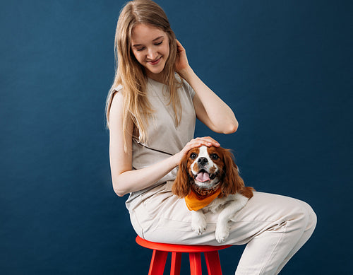 Young woman in casuals sitting on a red chair in studio with her