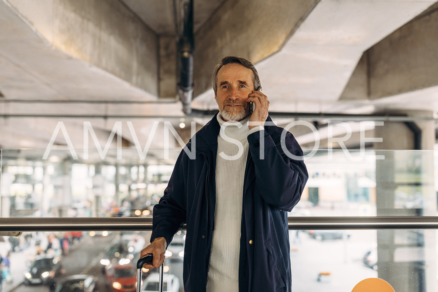 Senior tourist standing in airport terminal with luggage and talking on cell phone	