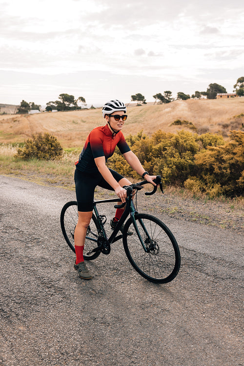 Woman cyclist in helmet and sunglasses relaxing during ride on c