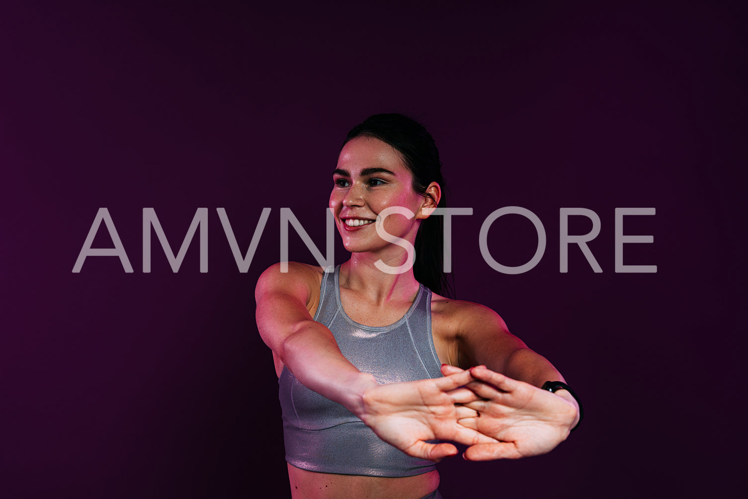 Close up of young smiling female stretching and flexing her hands over a magenta background in studio