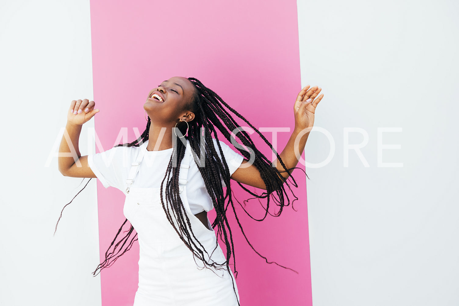 Happy girl in white clothes dancing and having fun at white wall with pink stripe