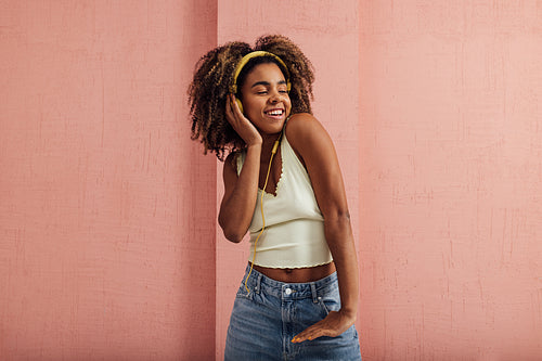 Young smiling woman enjoying music. Happy female wearing headphones and looking away.