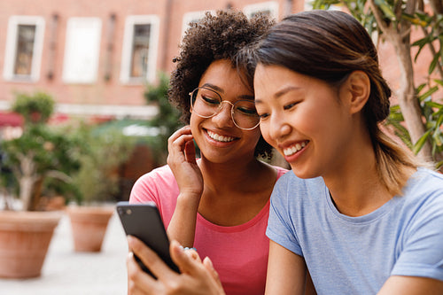 Two female friends live streaming from outdoor cafe