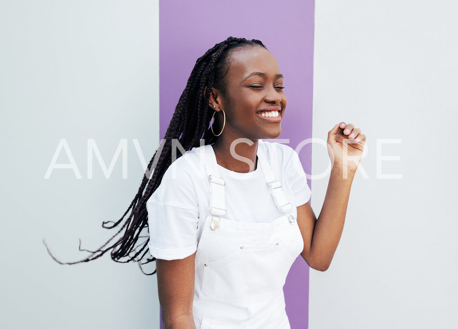 Young smiling female enjoying a good mood. Happy woman in white overalls standing at the wall.