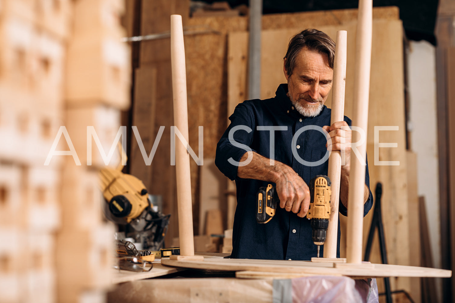 Carpenter drilling a hole in a wooden table at the workbench	