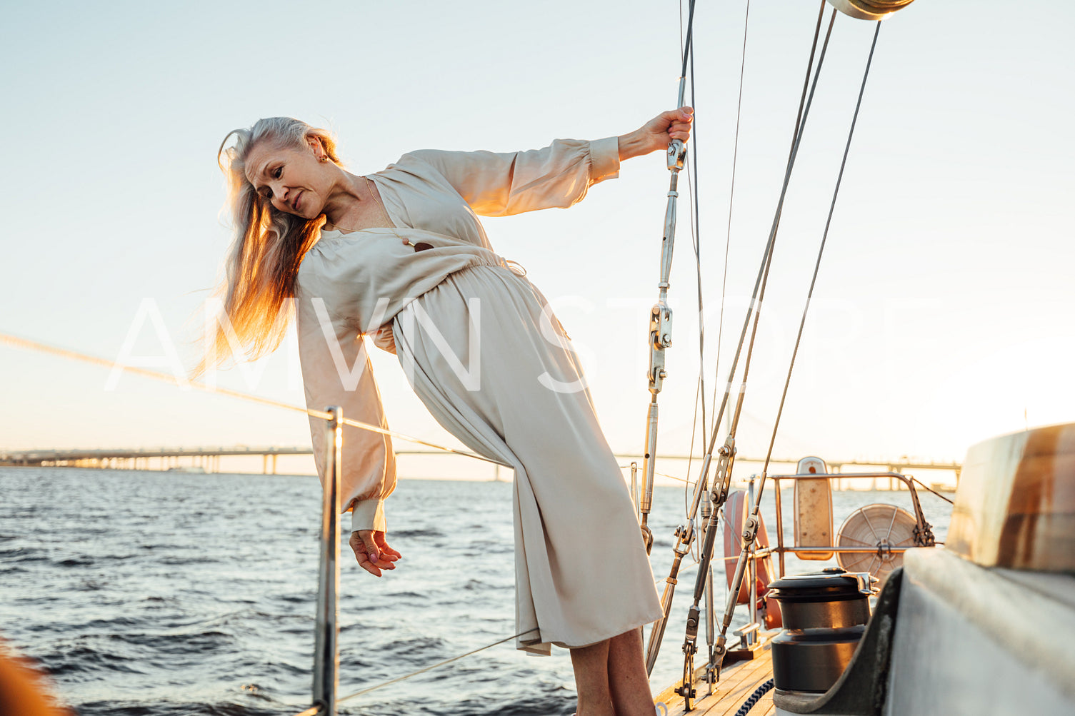 Beautiful senior woman with long hair posing on yacht and looking on water	