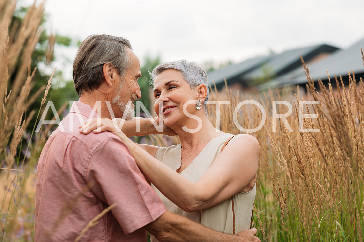 Two senior people standing together in the field and looking at each other