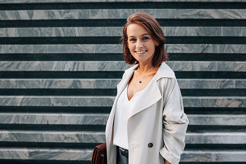 Portrait of a smiling middle-aged female with ginger hair looking at camera while standing outdoors