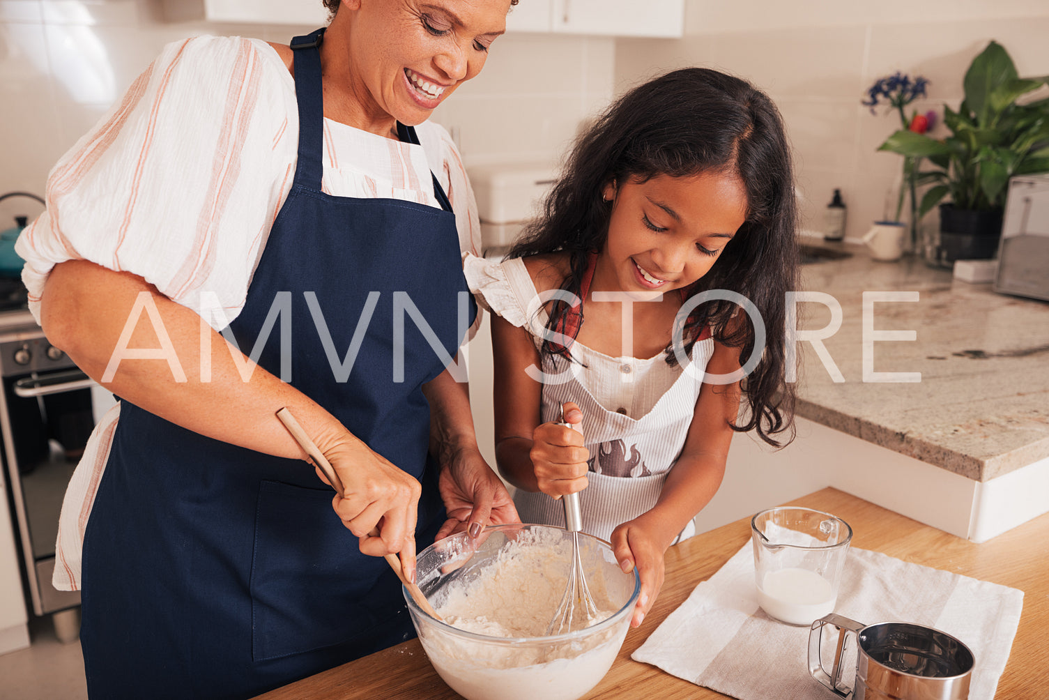 Girl and her grandma mix batter together in a glass bowl