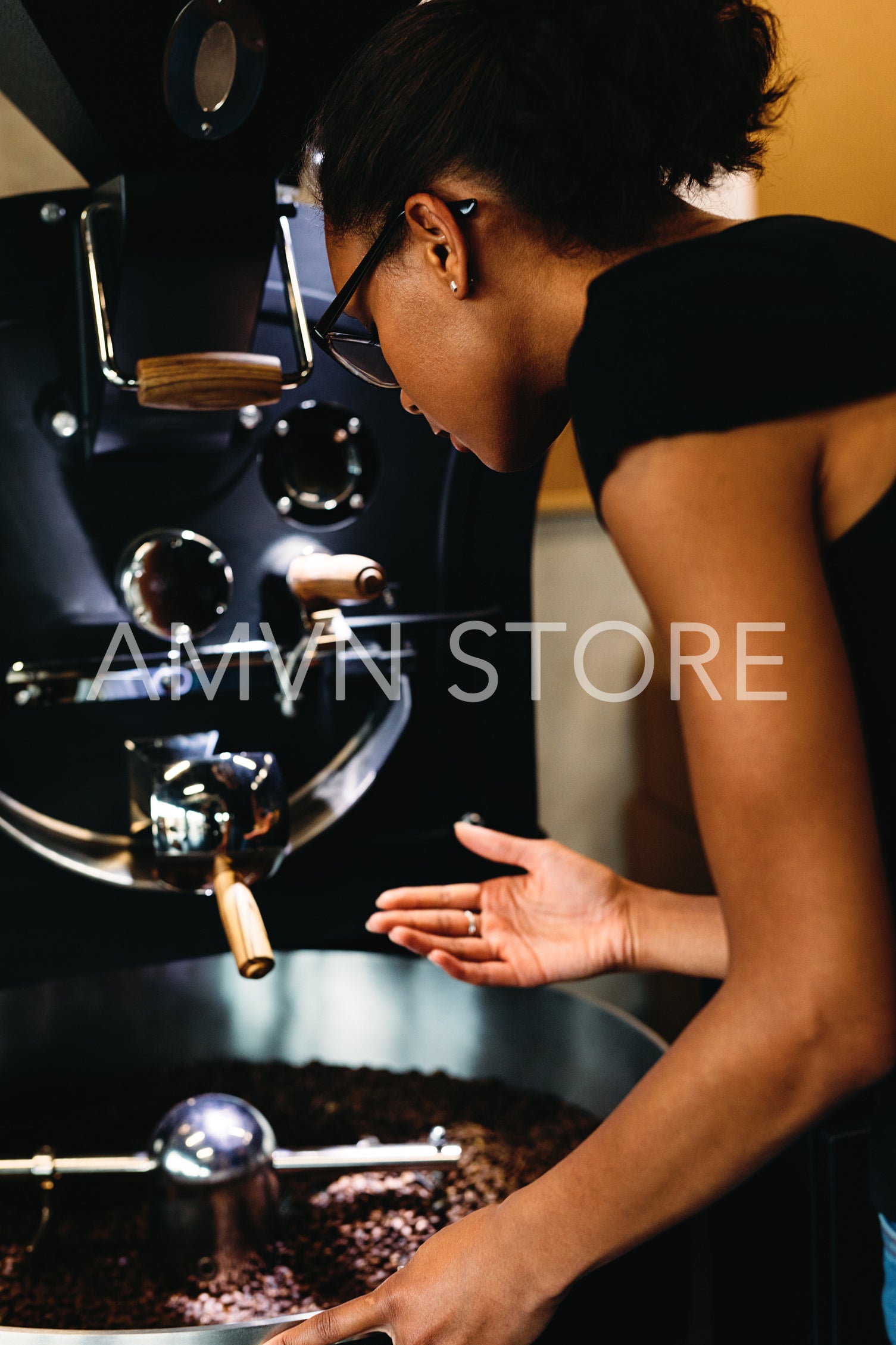 Young woman controlling process of a roasting coffee	