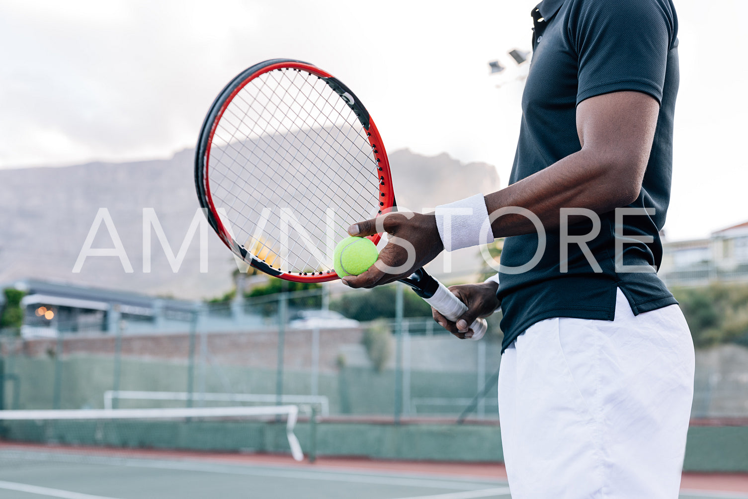 Cropped of an unrecognizable tennis player holding a racket and tennis ball while standing outdoors on a hard court