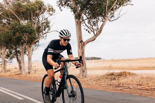 Female cyclist riding her pro bike fast on country road