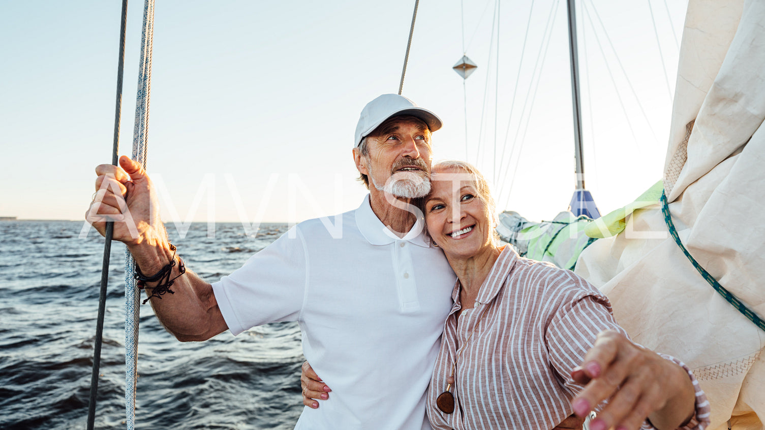 Portrait of a beautiful mature couple standing on a sailboat enjoying a vacation and looking away	