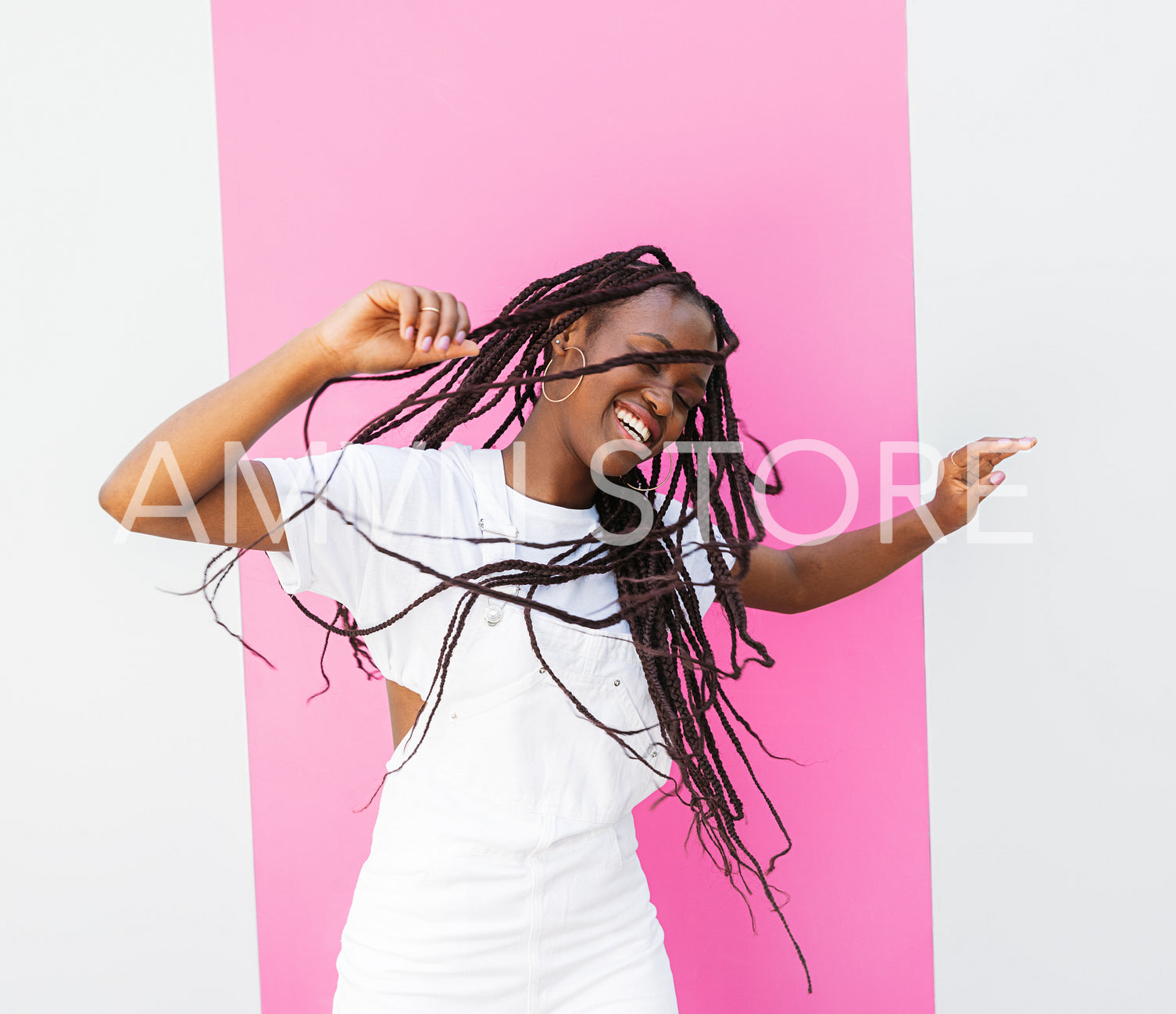 Happy girl in white overall dancing outdoors at a wall with pink stripe