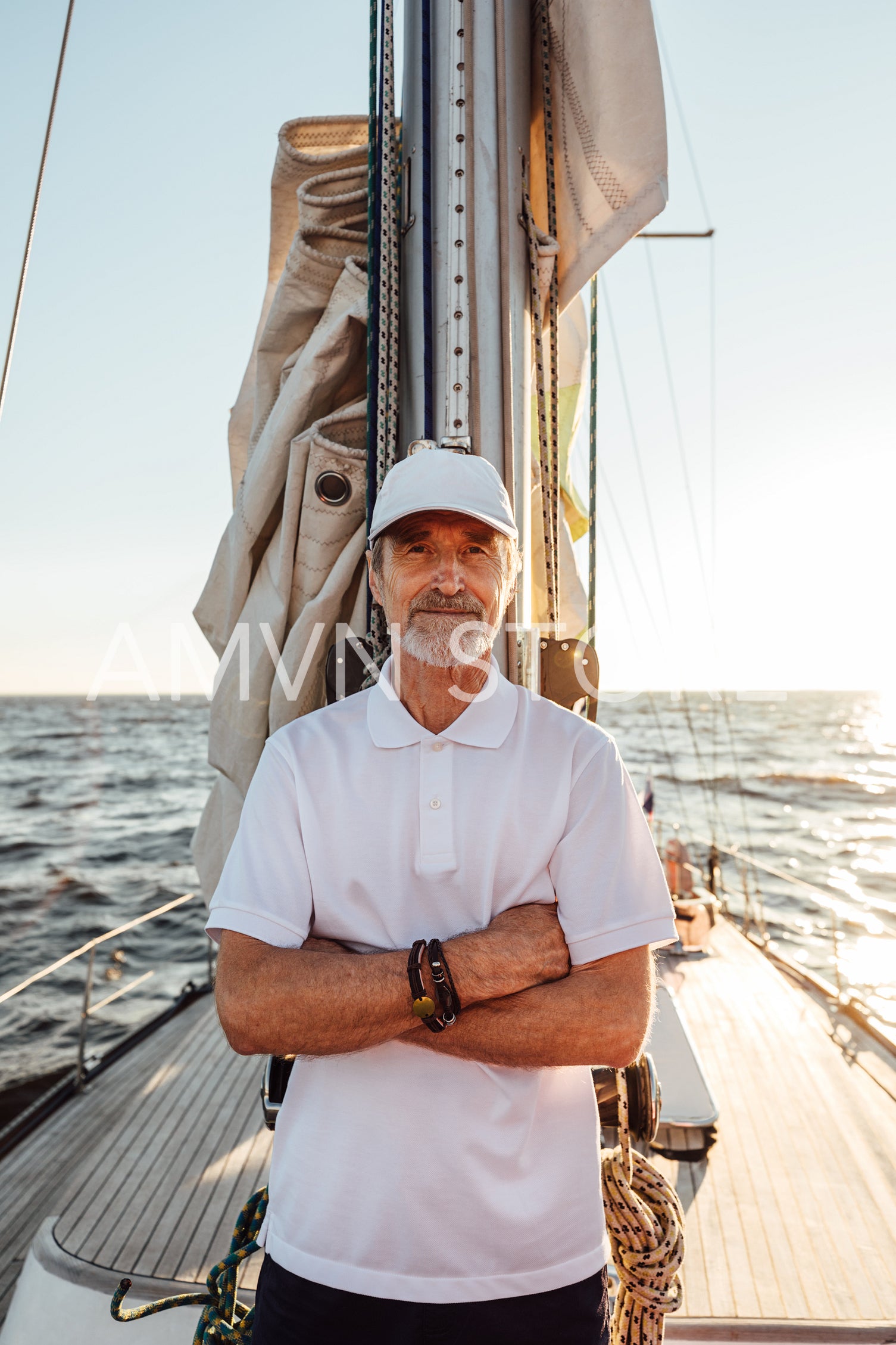 Portrait of a mature captain standing on his yacht at mast with crossed arms	