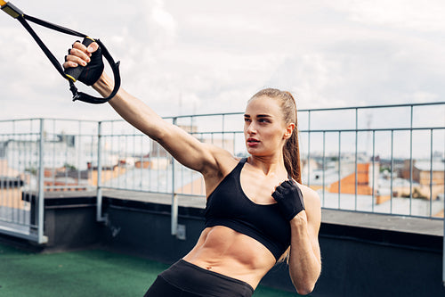 Woman doing push ups with fitness strap outdoors