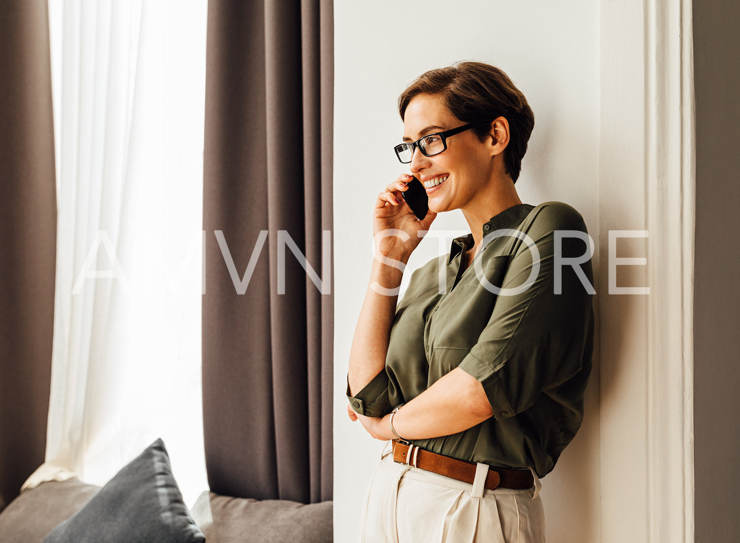 Caucasian businesswoman leaning a wall in apartment talking on mobile phone