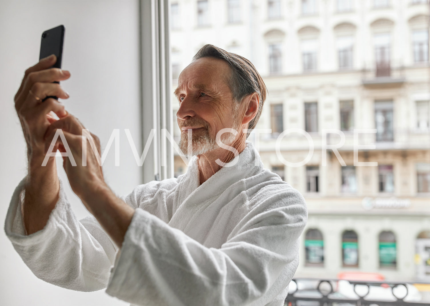 Handsome senior man taking a picture with a smartphone from a hotel room	