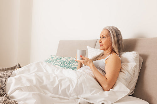 Senior woman with a cup. Aged female in the morning in bedroom.