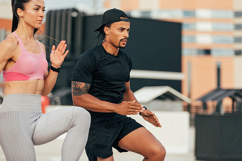 Fitness couple running together. Two people in sportswear exercising on rooftop.