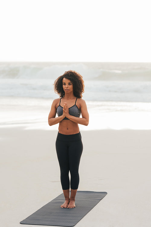 Woman practicing yoga on a beach at sunset