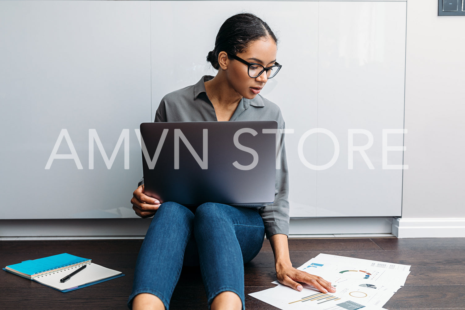 Female entrepreneur sitting down on the floor looking on documents. Freelance woman working from home.	